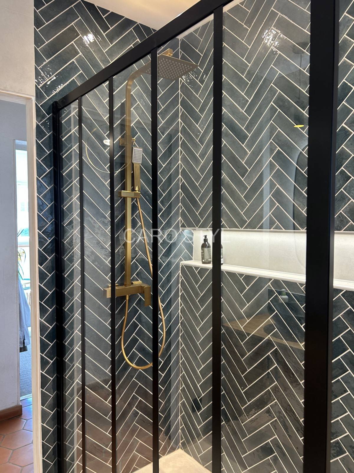 Paroi d'une cabine de douche aspect verrière pour révéler les carreaux Zellige et receveur style tadelakt dans le Var